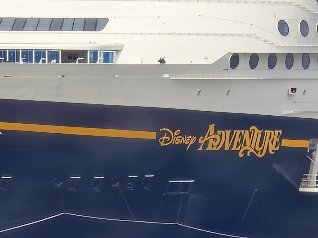 Nahaufnahme des Schiffsnames 'Disney Adventure' an der Seite eines Kreuzfahrtschiffs der Disney Cruise Line.