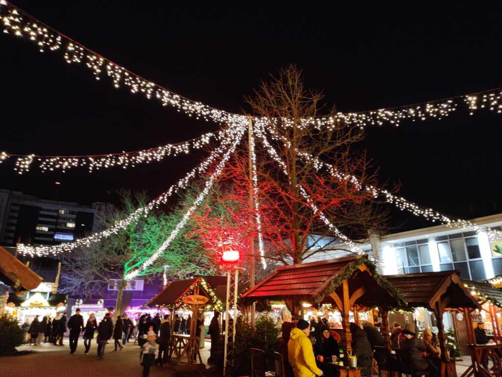 Beleuchteter Weihnachtsmarkt Bremerhaven mit festlich geschmückten Ständen und Besuchern bei Nacht.
