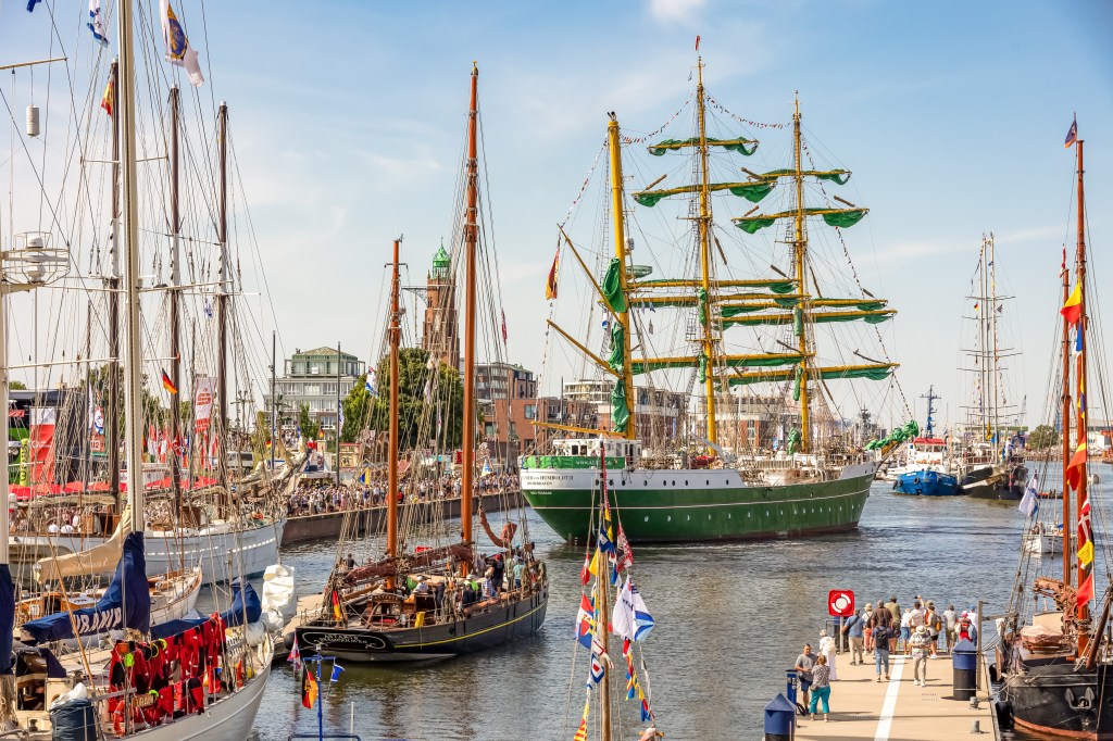 Blick auf den Neuen Hafen von Bremerhaven mit mehreren historischen Segelschiffen und Besuchern am Ufer während der Maritimen Tage.