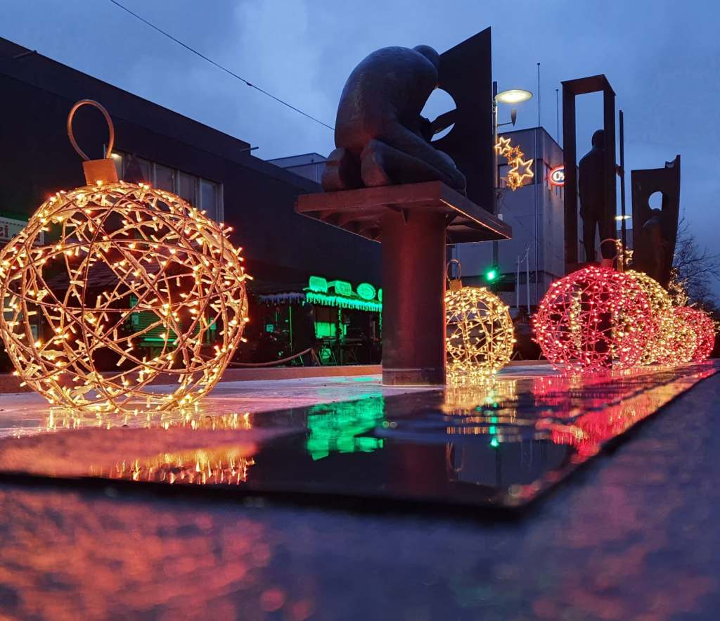 Festlich dekorierte Weihnachtslichter in Bremerhaven, mit leuchtenden Kugeln und einem skulpturalen Element im Hintergrund, während die Dämmerung einsetzt.